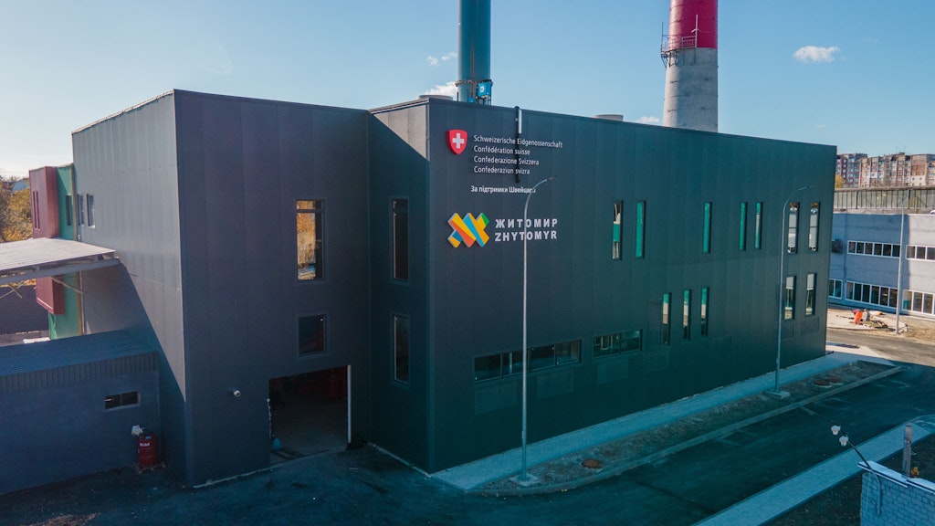 Power plant building in an industrial zone, with the logo of both the Swiss federal administration and the power plant on its façade
